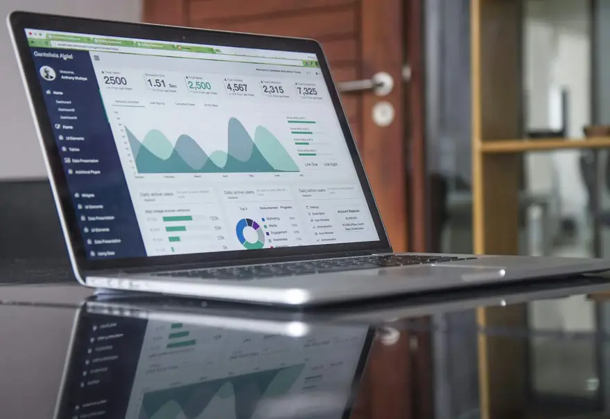 Portátil sobre una mesa mostrando un panel de analítica web con gráficas de visitas
