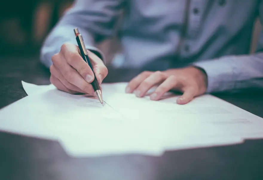 Persona firmando un presupuesto en papel sobre una mesa